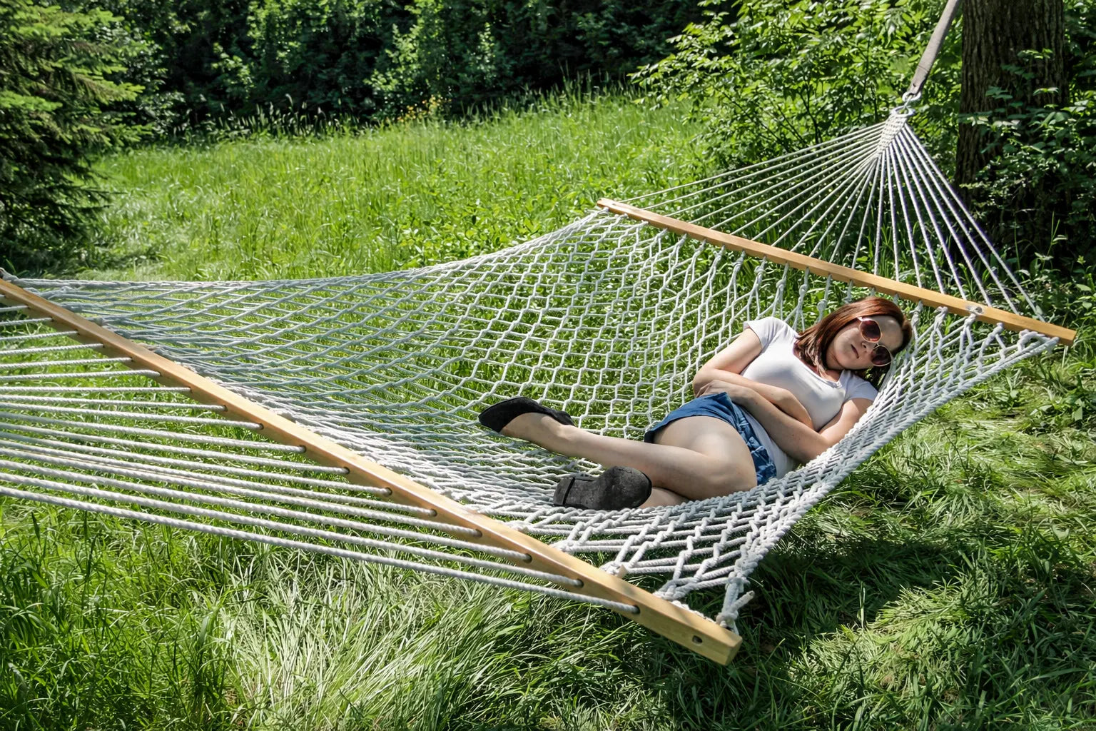 Woman relaxing in a hammock in a grassy outdoor setting 50501-PWT