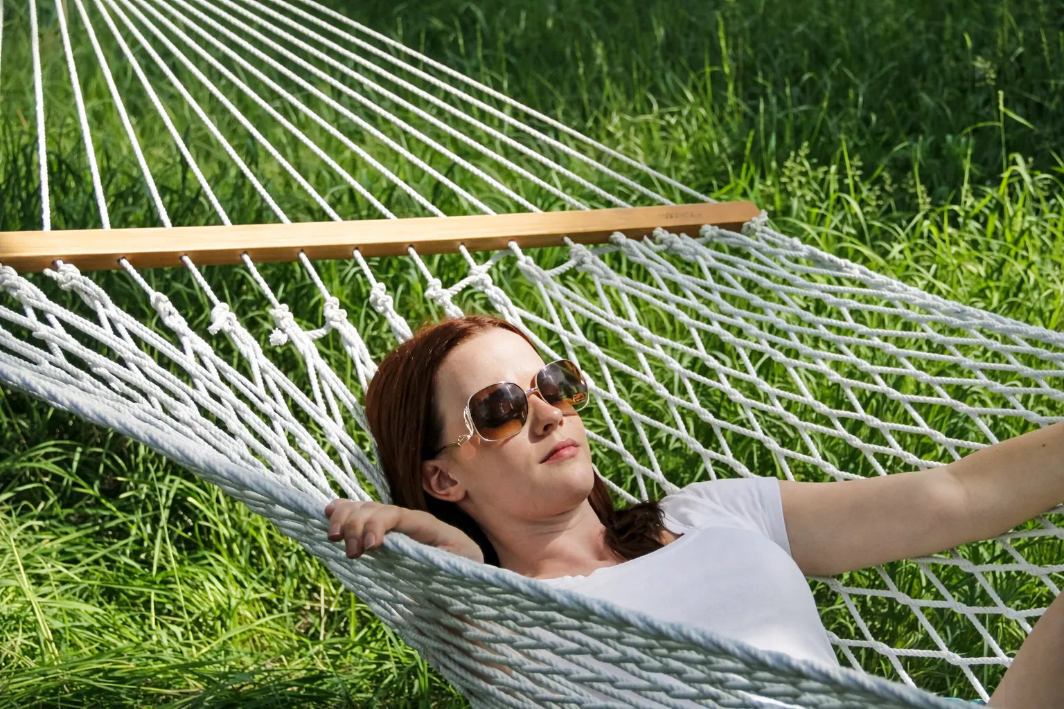 Woman relaxing in a white hammock on a grassy field 50501-PWT