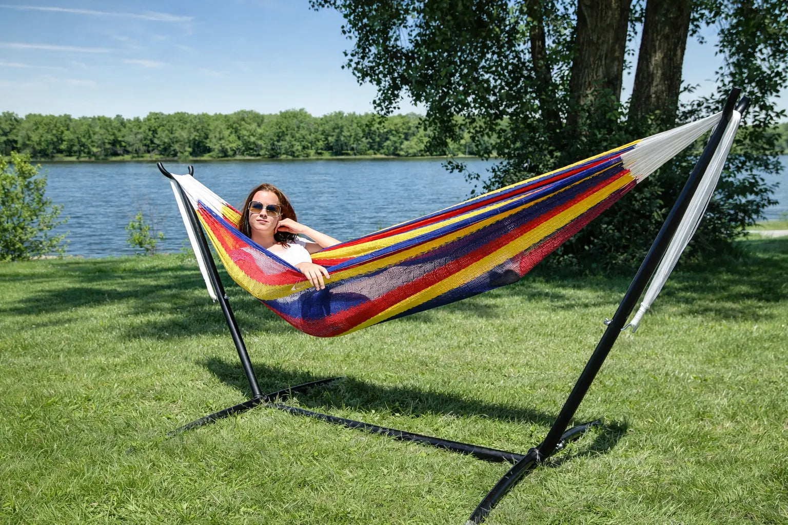 Woman relaxing in a colorful hammock by a lake