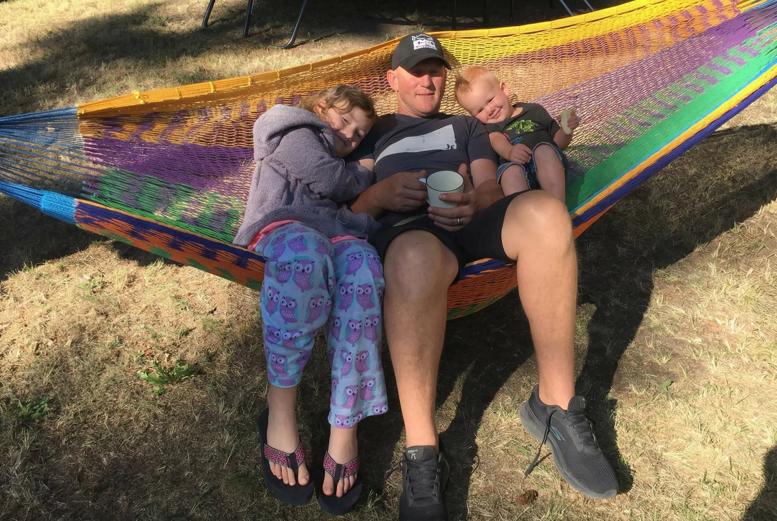 Man with two children in a colorful hammock on grass #24-MHXLTC-H