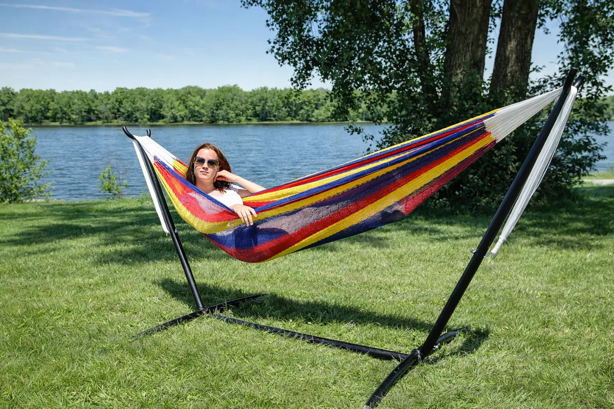 Woman relaxing in a colorful hammock by a lake
