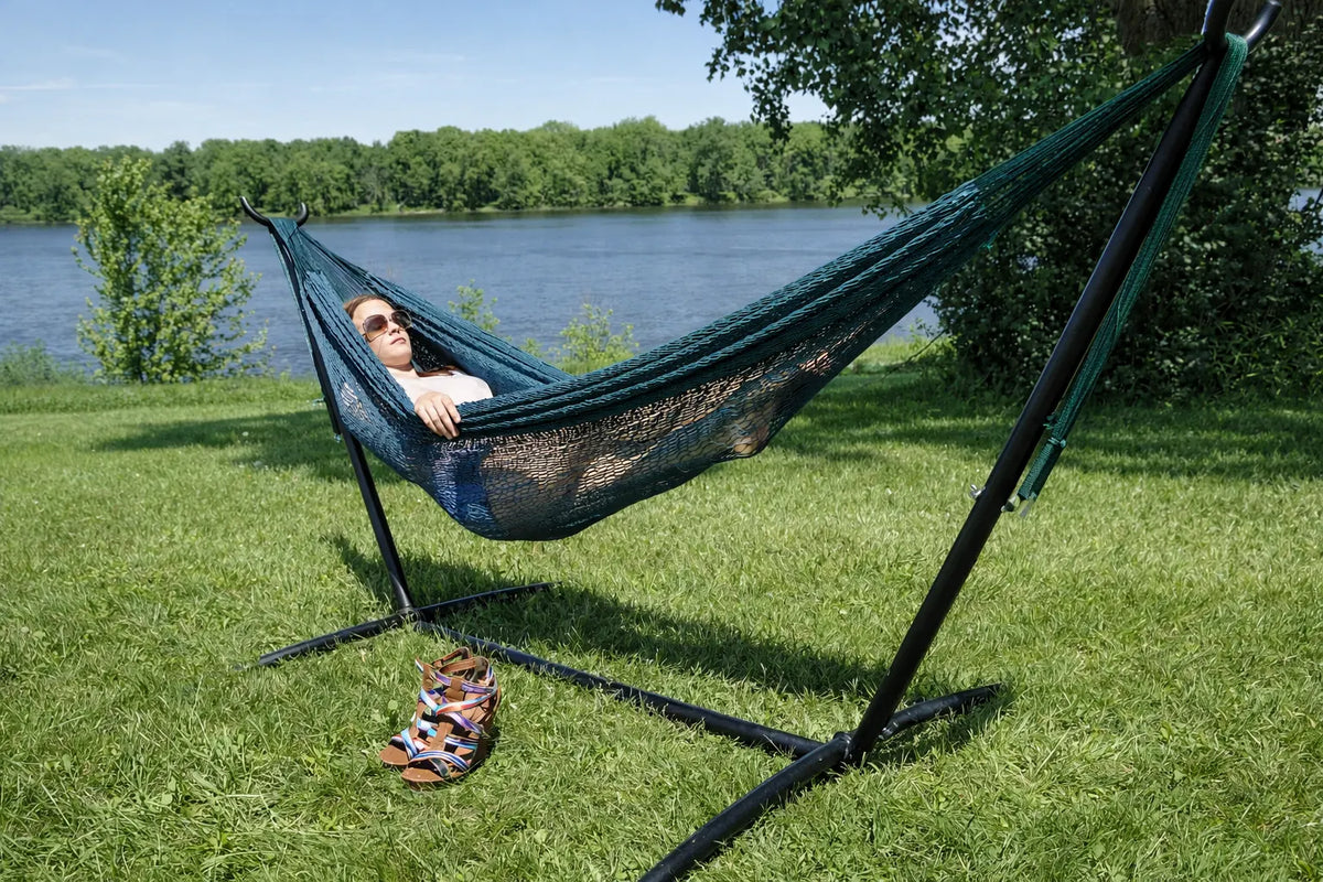 Person relaxing in a green hammock with a stand by a lake  #24-MHXLTC-FG+75121