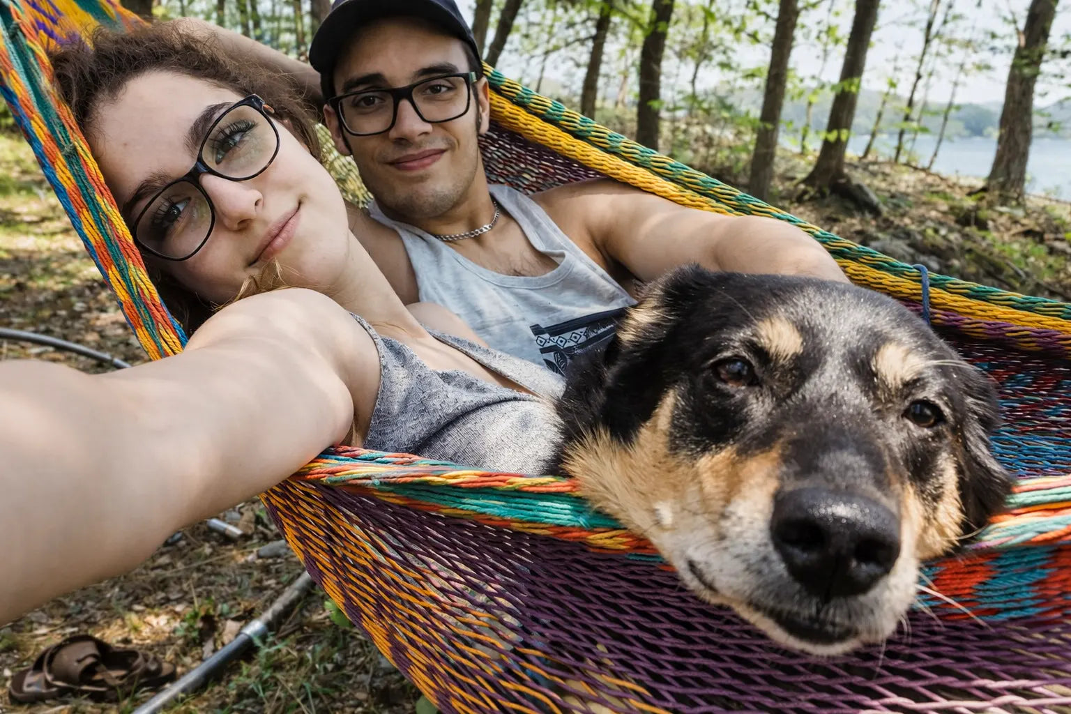 Two people in a hammock with a dog, surrounded by nature.  #24-MHXLTC-H+75121