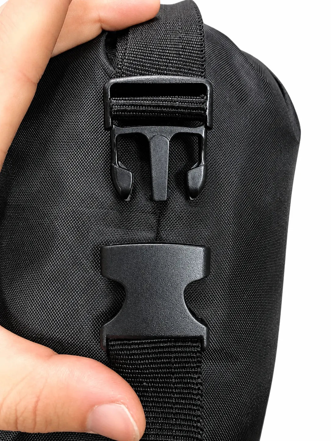 Black bag with a buckle detail held by a hand on a white background
