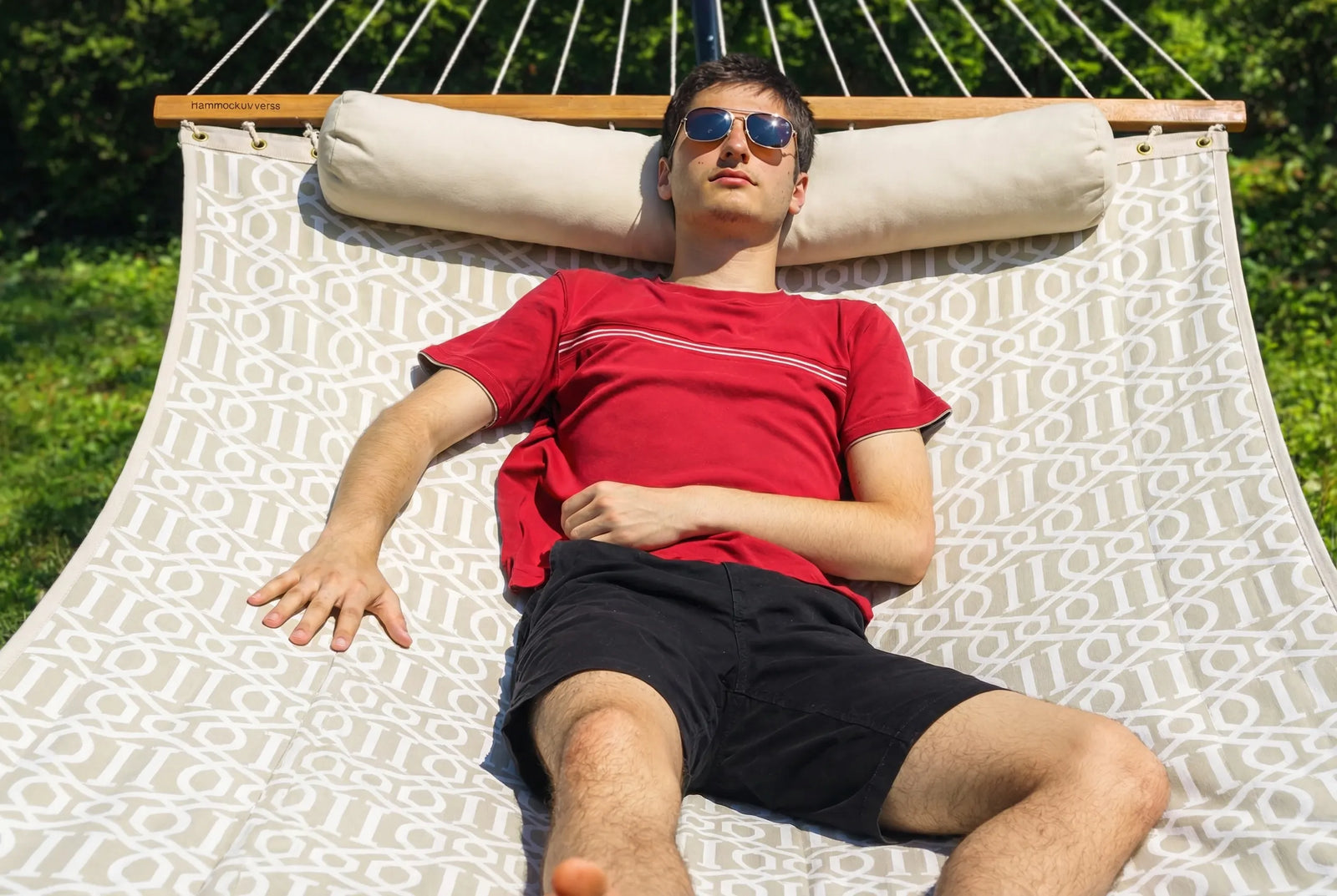 Man wearing sunglasses lying on a hammock with a patterned cushion QHD-COUNTRY
