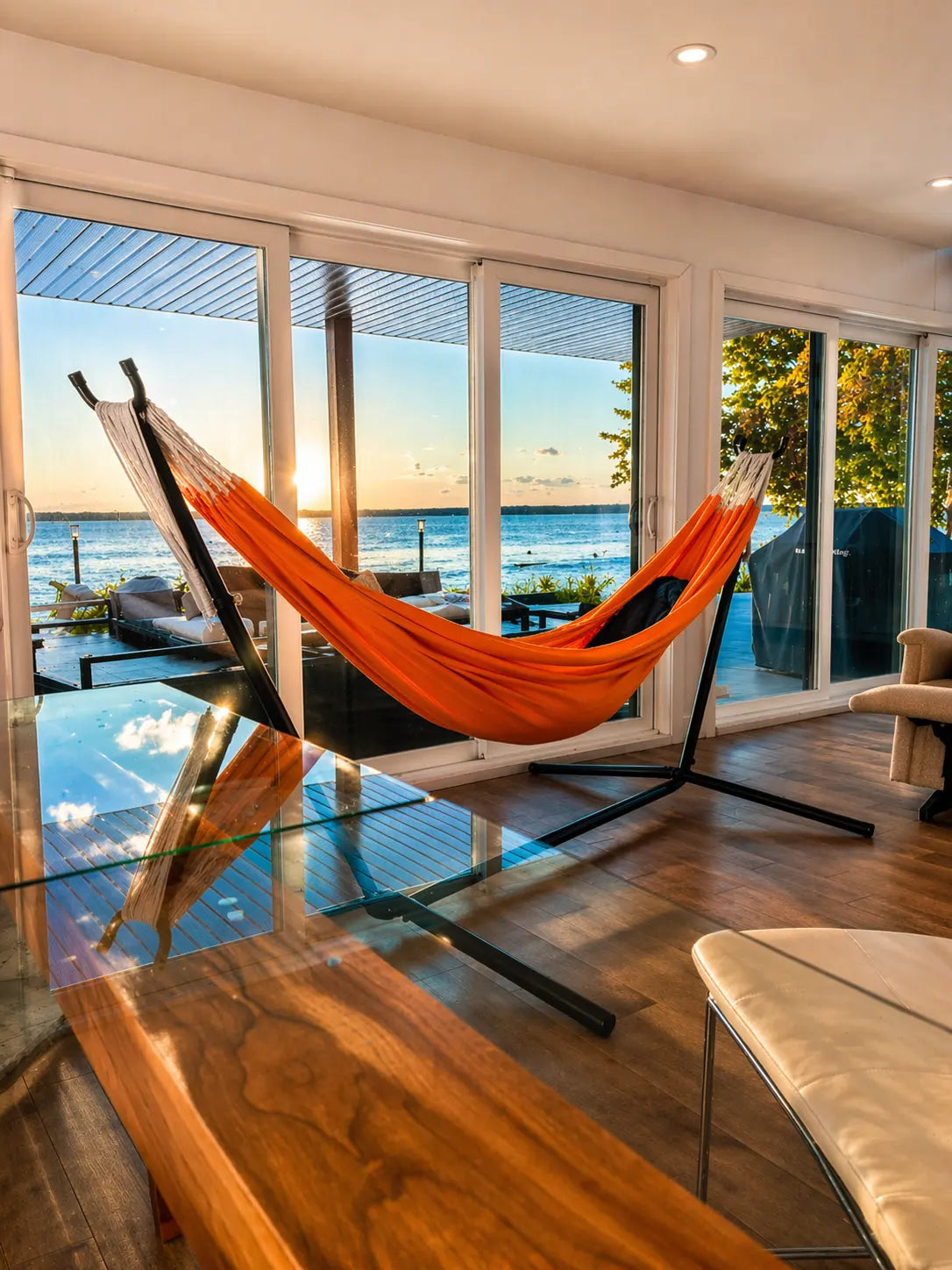 Orange hammock in a modern room with large windows overlooking water.